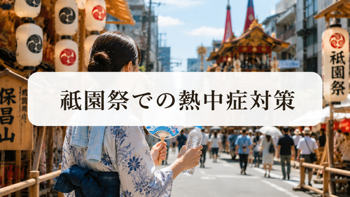 飲み物とうちわを持って祇園祭を歩く浴衣姿の女性